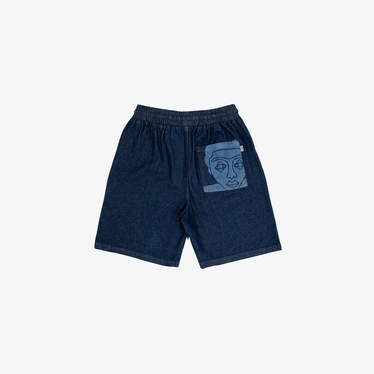 Short large avec dessin au laser en plein sur le devant et la poche plaquée dos, droite au porté. Taille élastiquée. Denim deep indigo rinse, 100% coton. Surpiqûres gros fil ton sur ton.