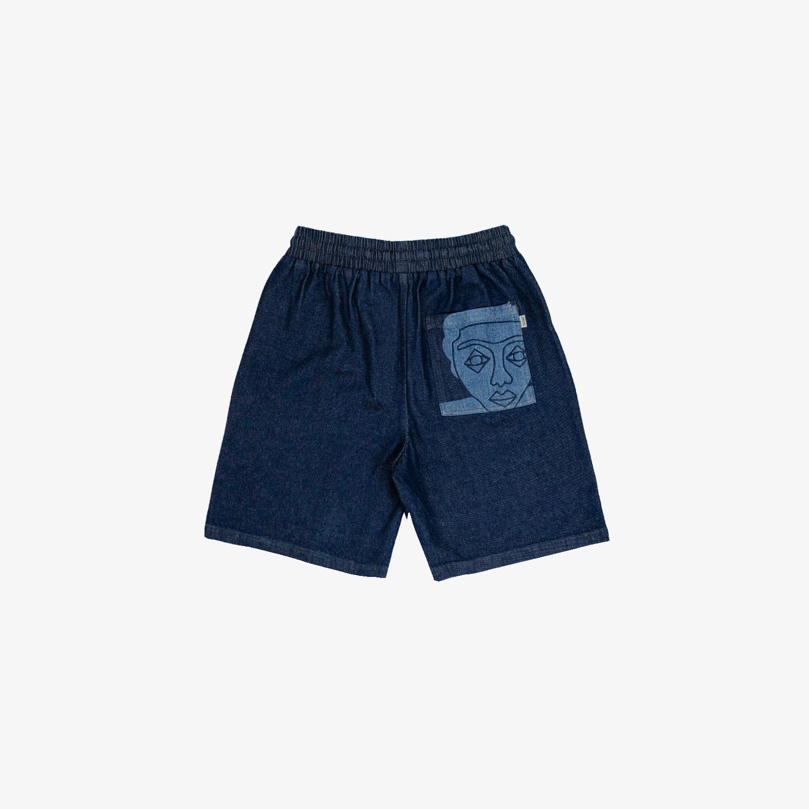 Short large avec dessin au laser en plein sur le devant et la poche plaquée dos, droite au porté. Taille élastiquée. Denim deep indigo rinse, 100% coton. Surpiqûres gros fil ton sur ton.