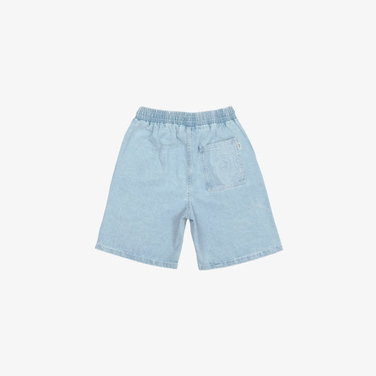 Short large avec dessin au laser en plein sur le devant et la poche plaquée dos, droite au porté. Taille élastiquée. Denim bleached, 100% coton. Surpiqûres gros fil ton sur ton.