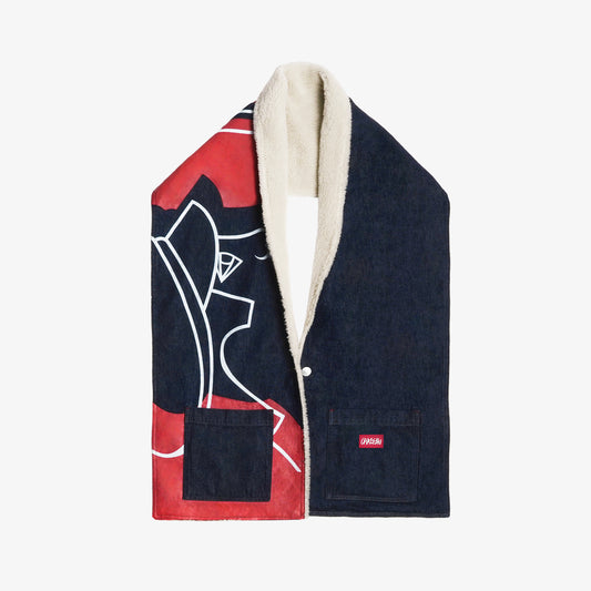 Grande écharpe en denim bleu intense 100% coton, pensée pour offrir un porté poncho grâce à un bouton intégré. Son volume enveloppant procure chaleur et élégance, tandis qu’une grande impression en sérigraphie habille la moitié de sa surface. Les aplats rouges et lignes blanches rendent hommage à la fresque Avec Vous. Finitions soignées avec surpiqûres ton sur ton, bouton embossé et gomme personnalisée.