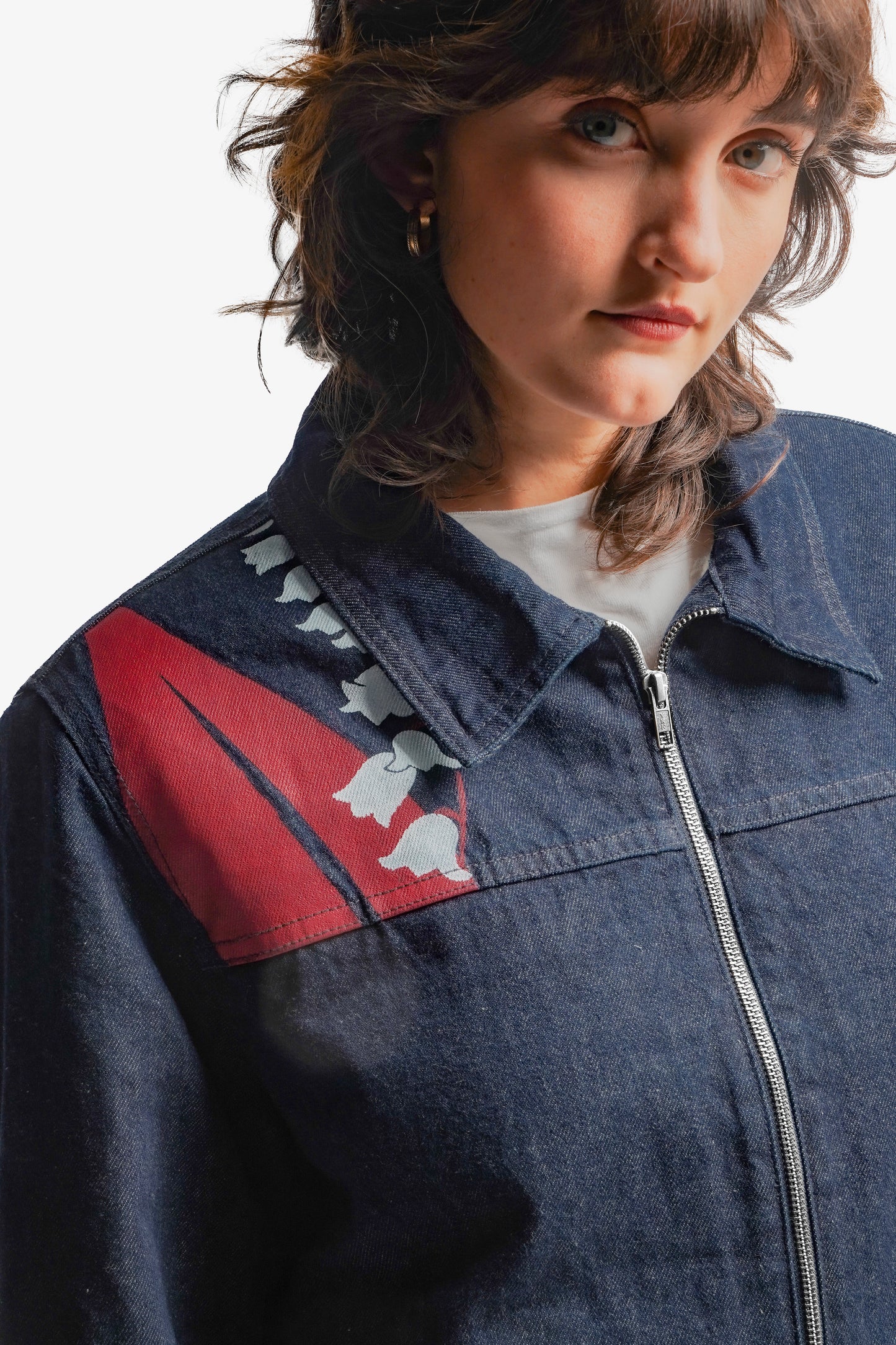 Veste en denim brut doublée en sherpa, alliant robustesse et confort. Ornée d’impressions sérigraphiques sur la poitrine et le dos, ses aplats rouges et lignes blanches s’inspirent directement de la fresque Avec Vous. Le denim bleu indigo 100% coton est sublimé par des surpiqûres ton sur ton, offrant un équilibre parfait entre design artistique et finition soignée. Vêtements de créateur. Veste Original.