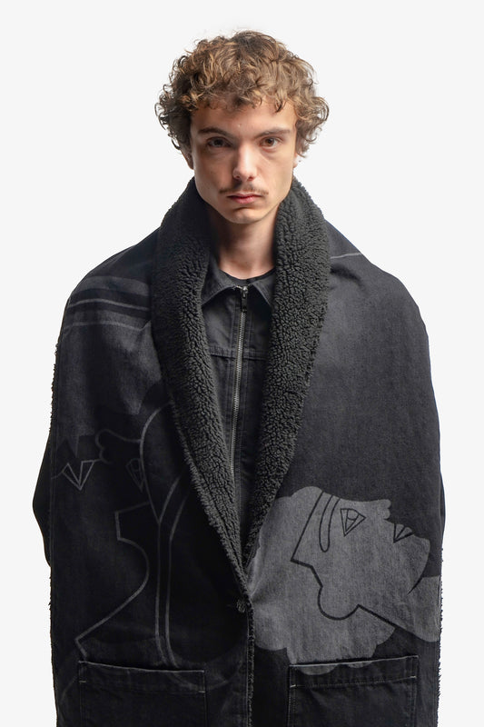 Grande écharpe noire en denim 100% coton, dotée d’un bouton permettant un porté poncho. Son volume généreux offre chaleur et confort, tandis que son design versatile permet de multiples styles de portés. Une impression laser couvre toute la surface, en hommage à la fresque Avec Vous. Surpiqûres contrastées grises, bouton et jacron en cuir teinté noir viennent parfaire son allure sophistiquée.