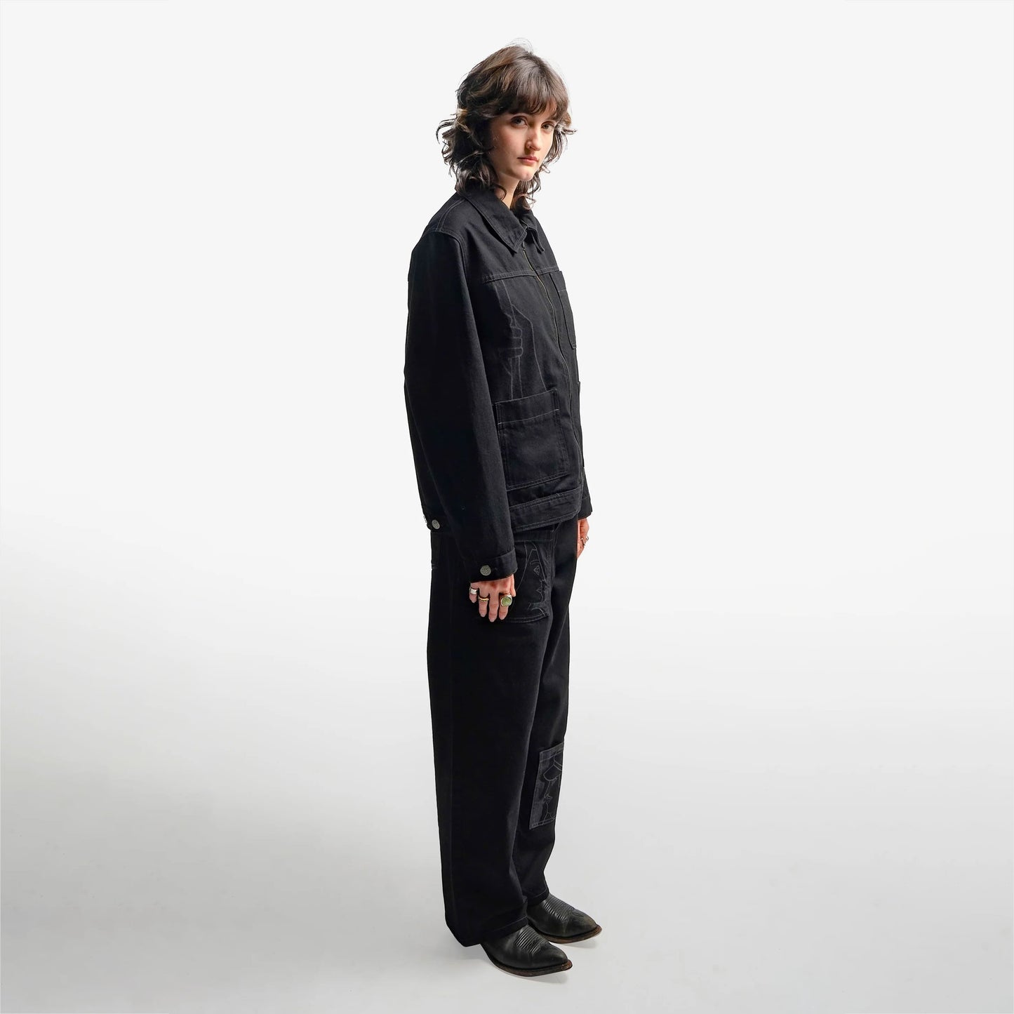 Jean brut confort en denim noir intense 100% coton. Son design minimaliste est rehaussé d’une impression au laser courant sur toute la jambe droite, inspirée de la fresque Avec Vous. Surpiqûres en contraste gris, jacron en cuir embossé noir et finitions précises en font une pièce aussi intemporelle qu’artistique.