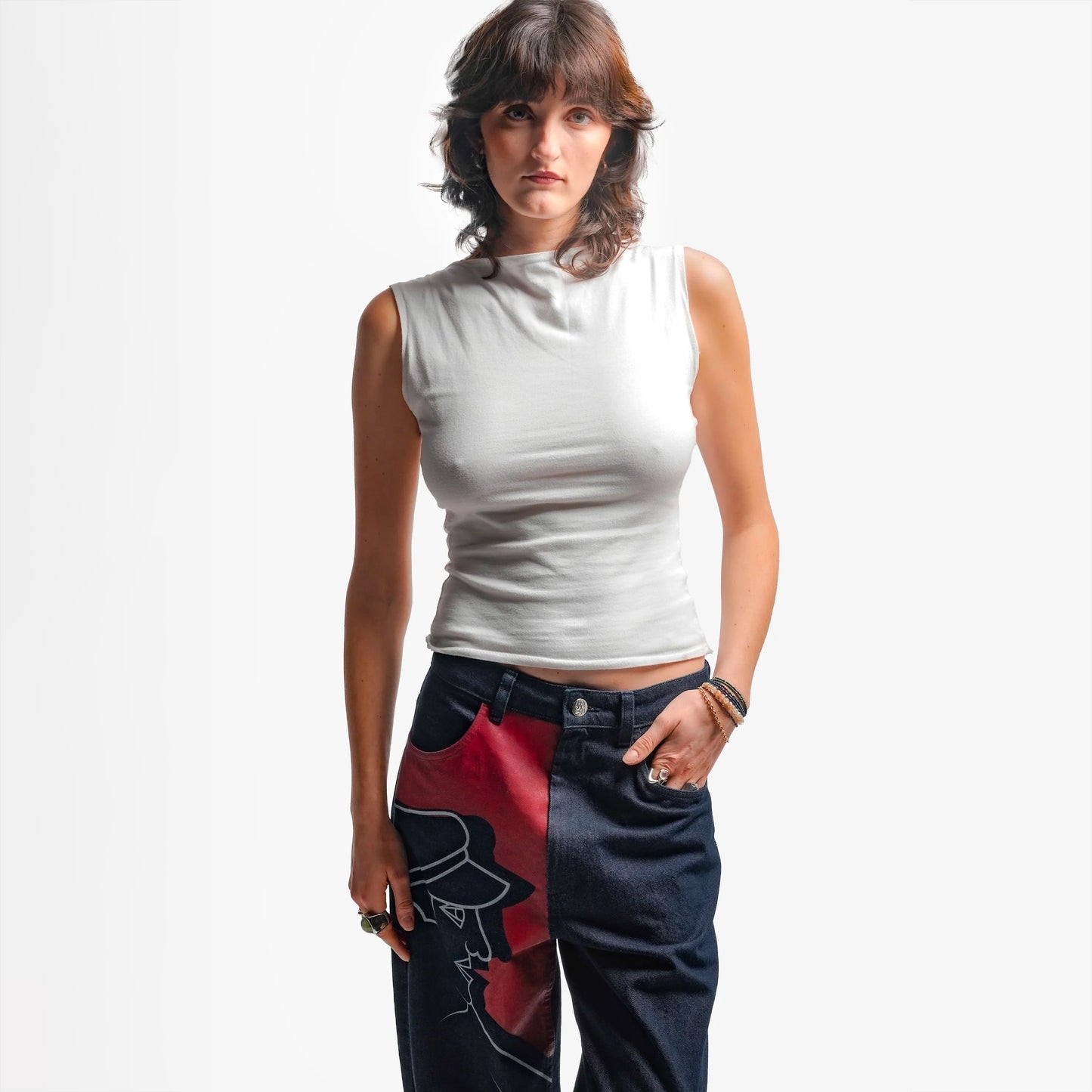 Une grande impression en sérigraphie recouvre toute la jambe droite, avec des aplats rouges et lignes blanches directement inspirés de la fresque Avec Vous. Confectionné avec des surpiqûres ton sur ton, il est signé d’un bouton et d’une gomme embossés et personnalisés.