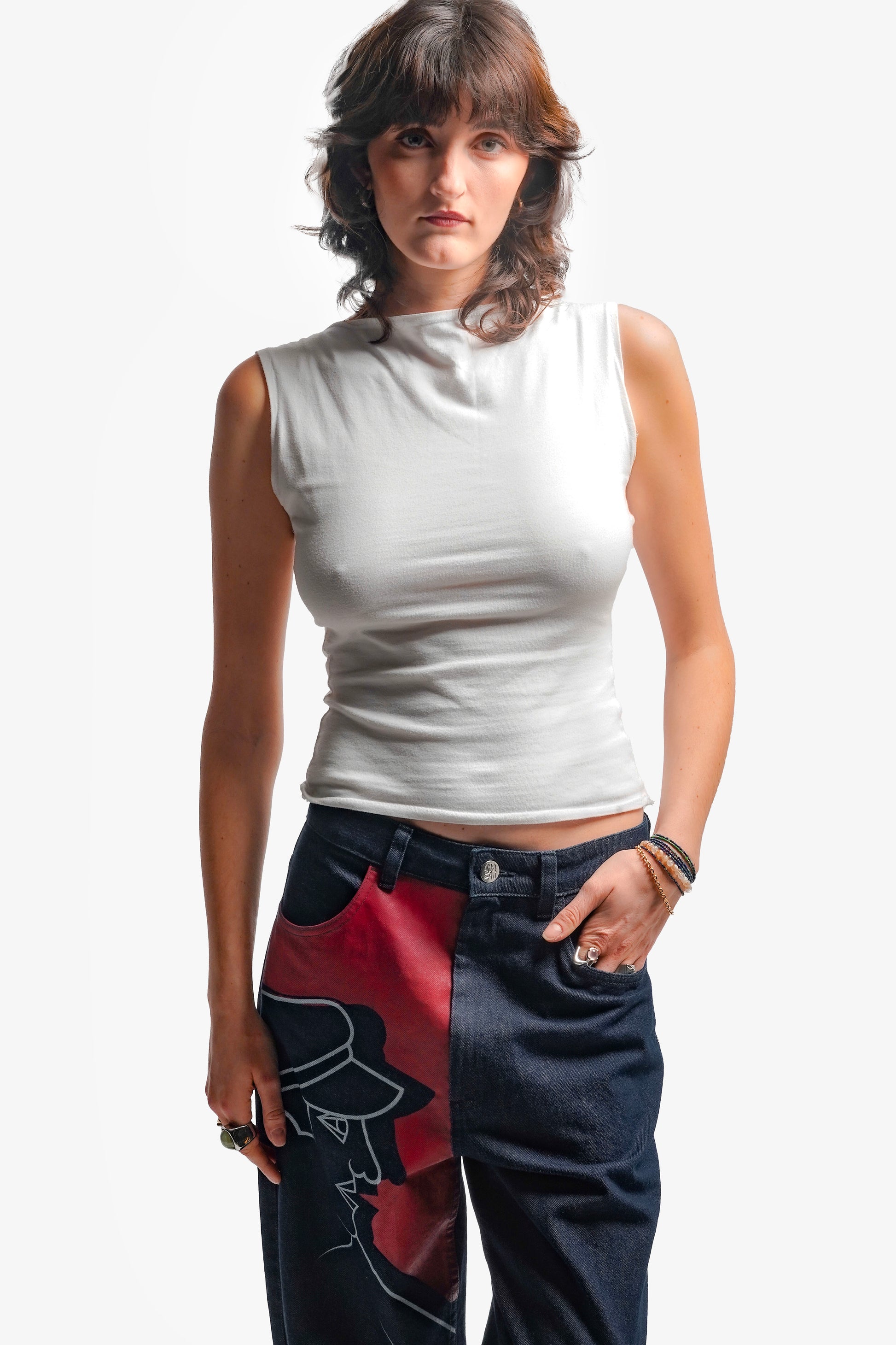 Une grande impression en sérigraphie recouvre toute la jambe droite, avec des aplats rouges et lignes blanches directement inspirés de la fresque Avec Vous. Confectionné avec des surpiqûres ton sur ton, il est signé d’un bouton et d’une gomme embossés et personnalisés.